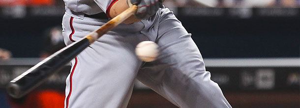 A baseball player swings at the ball on the plate in an MLB game