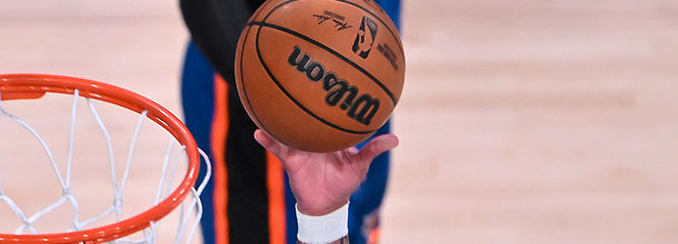 An NBA player's hand and the ball and the basket