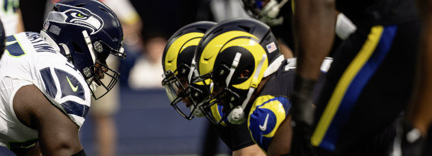 Football players from the Seattle Seahawks and the Los Angeles Rams line up for a snap in an NFL game