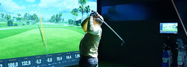 A golf player hits a shot on a golf simulator