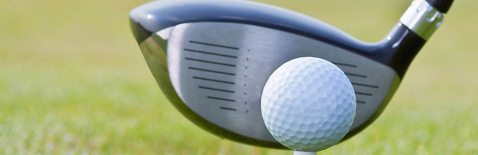 A golf ball on a tee and the head of the driver
