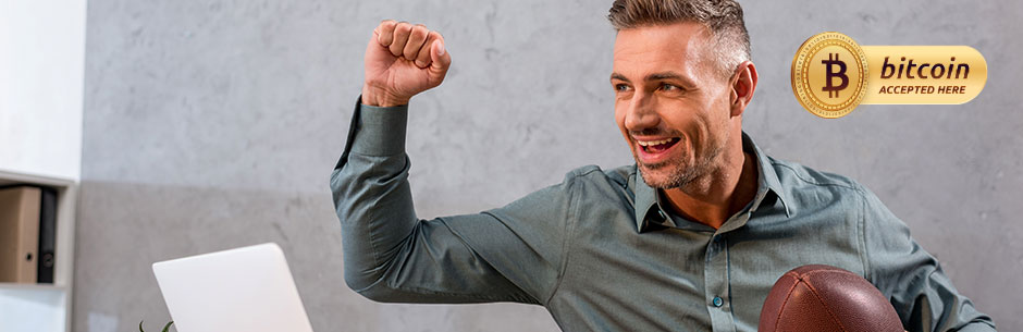 Man holding an American football celebrates in front of his laptop