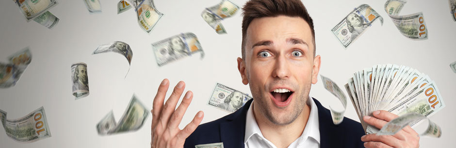 A young man holding dollar notes looks very happy