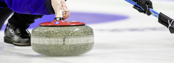 A curler sets the stone down the ice