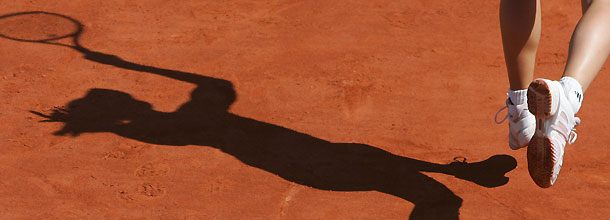 A tennis player in shadow on a clay court at the French Open