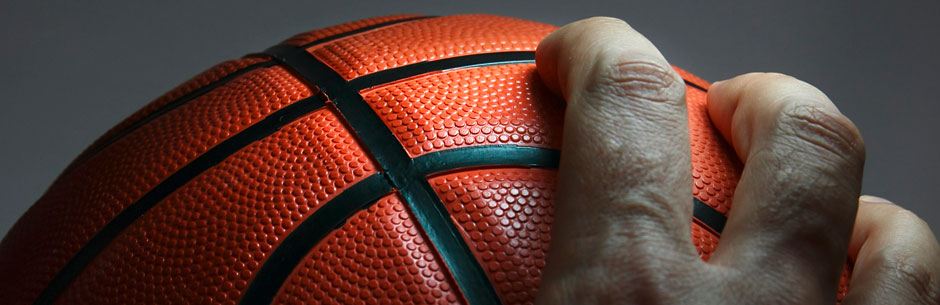 A hand clasps a basketball in the NCAAB March Madness tournament